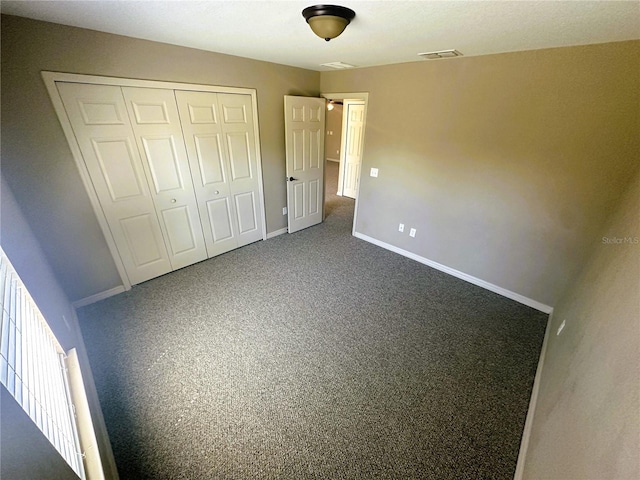 unfurnished bedroom with a closet, visible vents, carpet, and baseboards