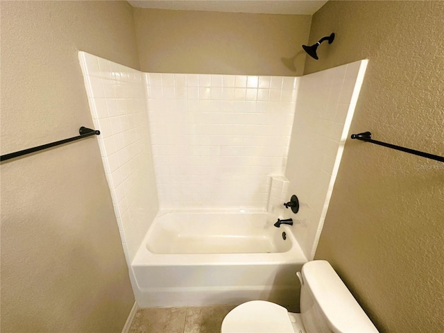 bathroom featuring toilet,  shower combination, and a textured wall