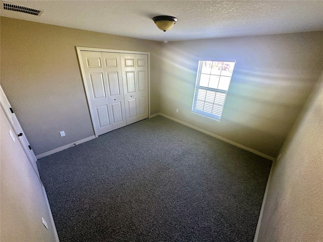 unfurnished bedroom featuring visible vents, baseboards, carpet floors, a closet, and a textured ceiling