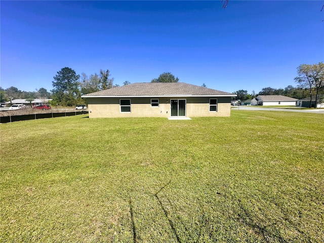 rear view of property featuring stucco siding and a yard