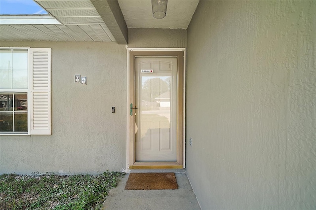 doorway to property featuring stucco siding