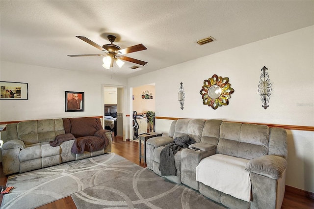 living area featuring ceiling fan, visible vents, a textured ceiling, and wood finished floors