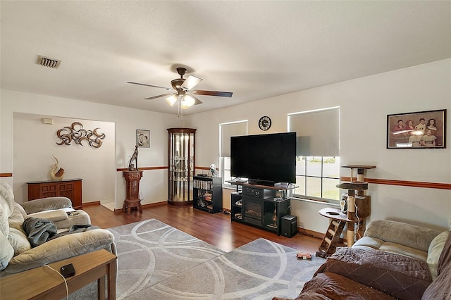 living area featuring ceiling fan, visible vents, baseboards, and wood finished floors