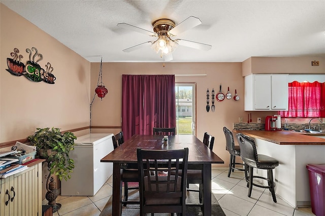 dining space featuring light tile patterned floors, a textured ceiling, and a ceiling fan