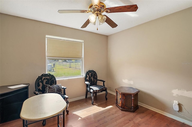 living area featuring wood finished floors, baseboards, and ceiling fan