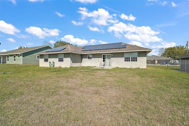 back of property featuring a yard, solar panels, and fence