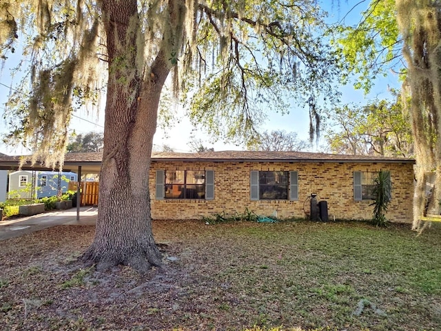 view of front of home featuring an attached carport, brick siding, and a front yard