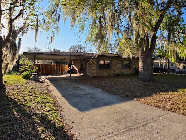 ranch-style house featuring a carport, concrete driveway, and brick siding