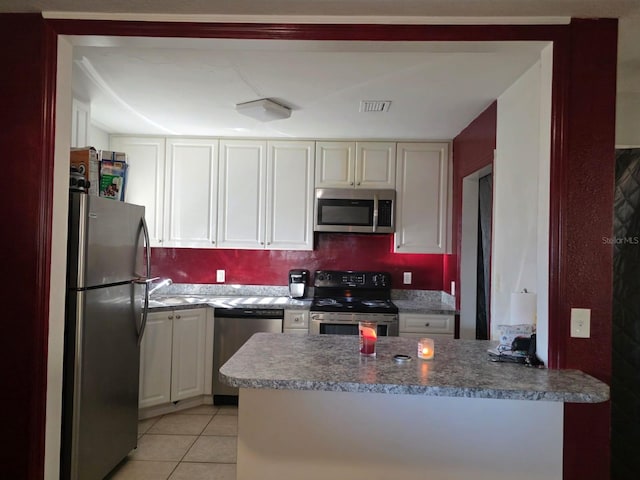 kitchen featuring visible vents, a sink, stainless steel appliances, a peninsula, and light tile patterned floors