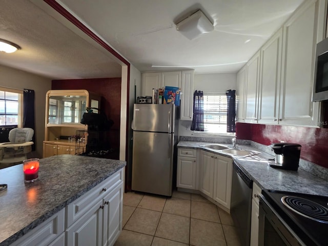 kitchen featuring light tile patterned floors, white cabinetry, stainless steel appliances, and a sink