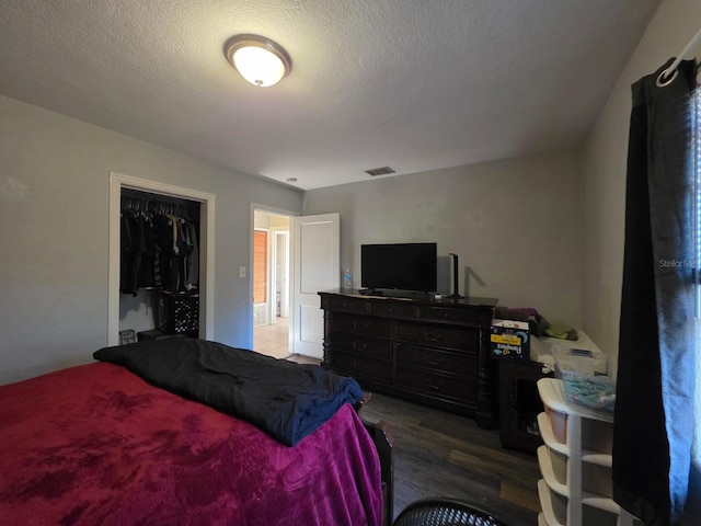 bedroom featuring visible vents, a textured ceiling, and wood finished floors