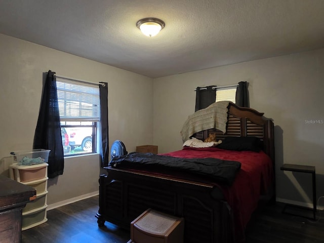 bedroom with a textured ceiling, baseboards, and wood finished floors