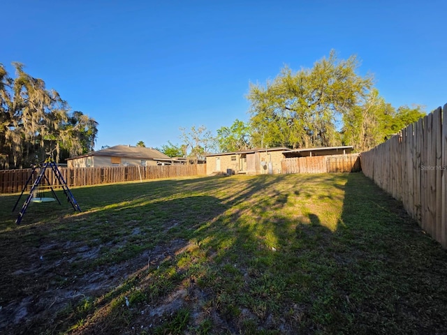 view of yard with a fenced backyard and a playground