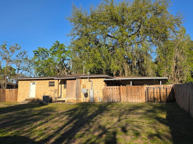 back of property with a lawn, a fenced backyard, and entry steps