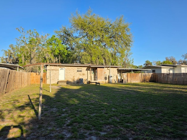 rear view of house with central AC unit, a lawn, entry steps, and a fenced backyard