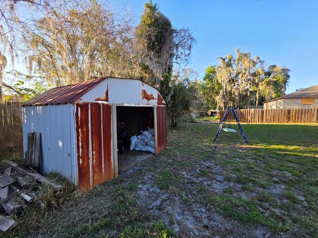 view of yard featuring an outbuilding, a playground, fence, and a shed