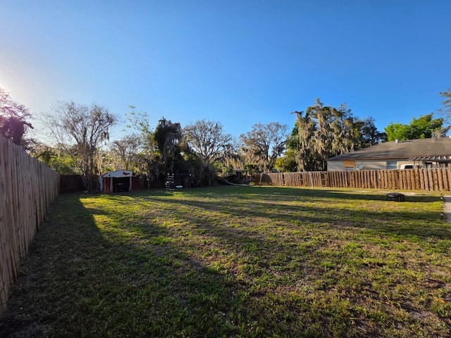 view of yard with an outdoor structure, a fenced backyard, and a storage shed