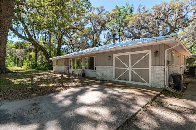 view of side of property with an outbuilding, central AC unit, brick siding, and metal roof