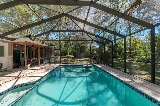 pool featuring glass enclosure, a ceiling fan, and a patio