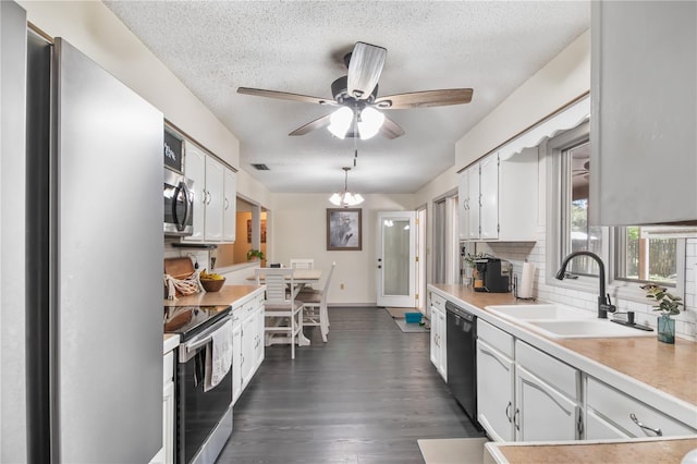 kitchen featuring backsplash, light countertops, white cabinets, stainless steel appliances, and a sink