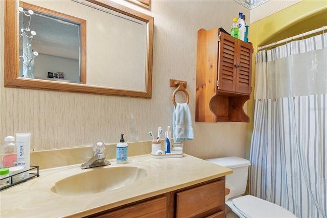 bathroom featuring curtained shower, toilet, vanity, and wallpapered walls