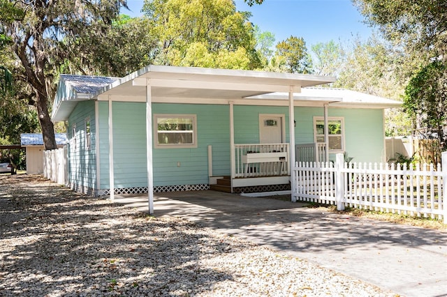 view of front of property with a carport, covered porch, concrete driveway, and fence