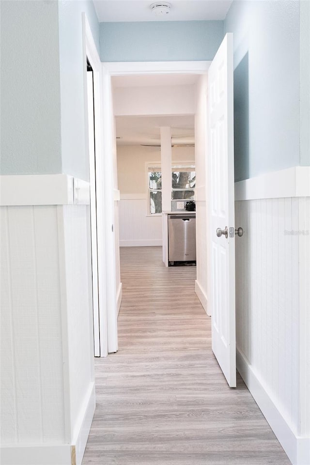 corridor featuring light wood-style floors and wainscoting