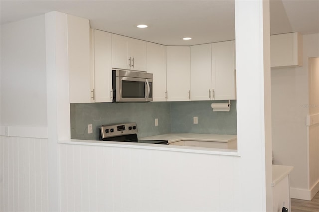 kitchen with backsplash, appliances with stainless steel finishes, white cabinetry, and light countertops