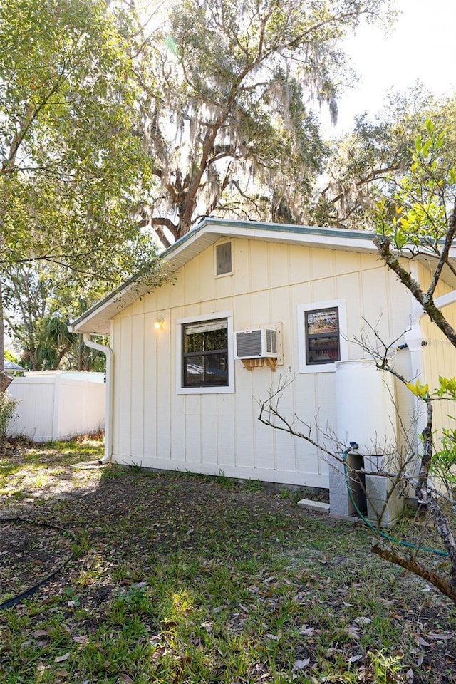 view of property exterior with a wall mounted AC and fence