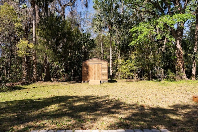 view of yard featuring a wooded view, a storage unit, and an outdoor structure