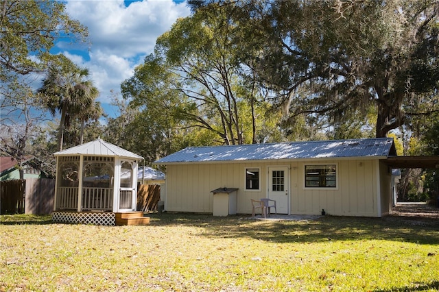 back of house with a yard, board and batten siding, metal roof, and fence