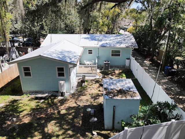 exterior space with a deck, an outdoor structure, cooling unit, and a fenced backyard