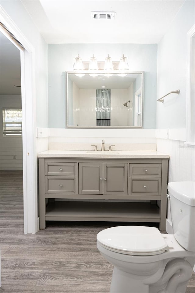 full bathroom with vanity, toilet, wood finished floors, and a wainscoted wall