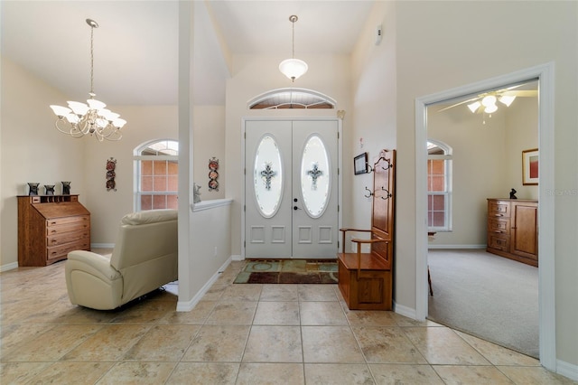 foyer entrance featuring light tile patterned floors, baseboards, light colored carpet, and a chandelier