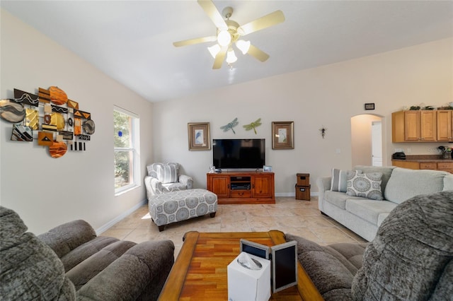 living area with a ceiling fan, baseboards, lofted ceiling, light tile patterned flooring, and arched walkways