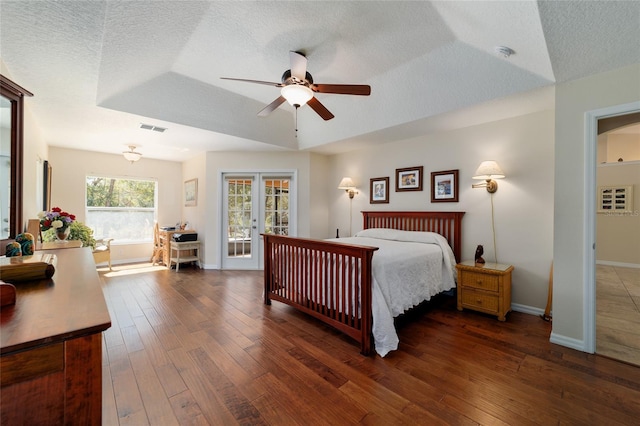 bedroom with a ceiling fan, baseboards, dark wood-style floors, visible vents, and a textured ceiling