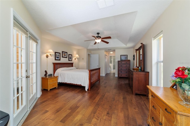 bedroom featuring a raised ceiling, visible vents, and dark wood-type flooring