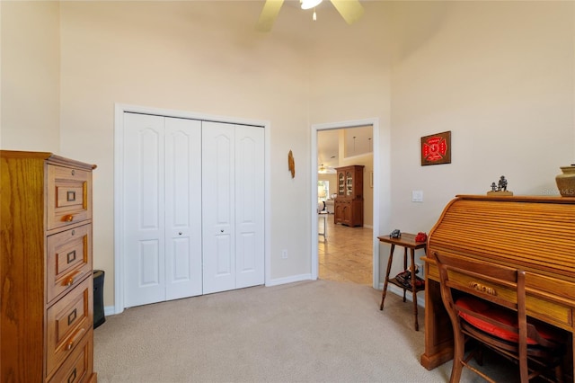 office space featuring baseboards, light colored carpet, and a ceiling fan