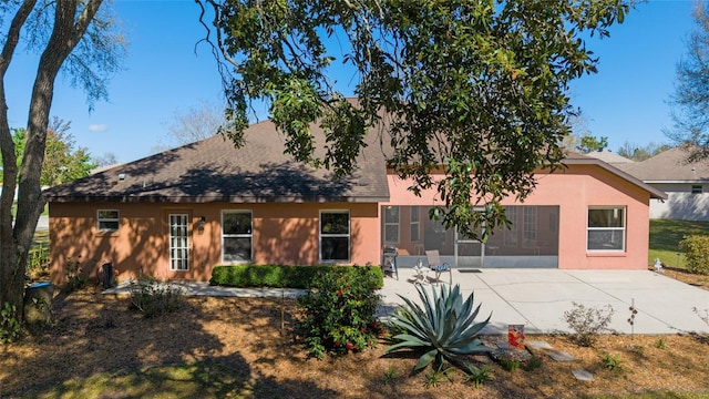 view of front of property with stucco siding, a patio, and a shingled roof