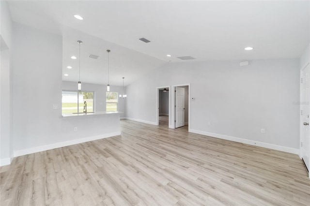 empty room featuring lofted ceiling, light wood-style flooring, visible vents, and a sink