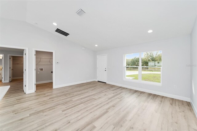 empty room with vaulted ceiling, baseboards, visible vents, and light wood-type flooring