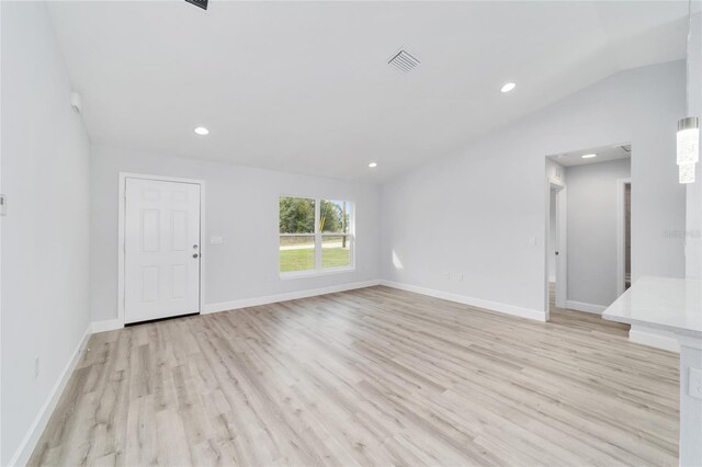 unfurnished living room featuring recessed lighting, baseboards, vaulted ceiling, and light wood finished floors