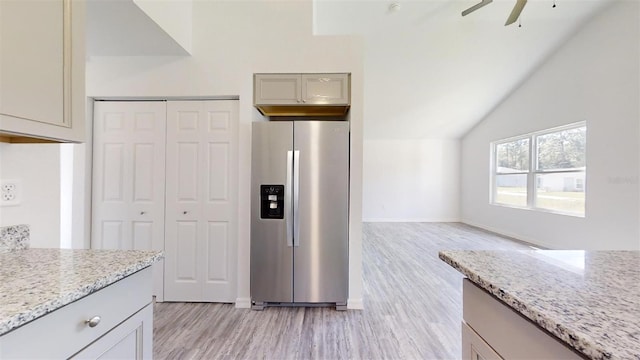 kitchen featuring light stone counters, gray cabinetry, ceiling fan, stainless steel refrigerator with ice dispenser, and light wood-type flooring