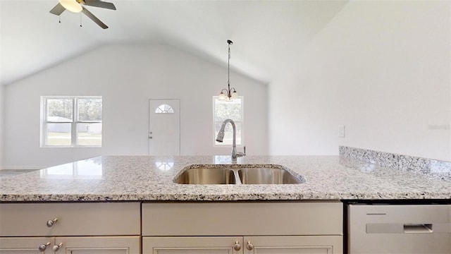 kitchen featuring vaulted ceiling, light stone counters, white dishwasher, a ceiling fan, and a sink