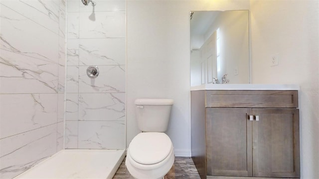 bathroom featuring a tile shower, toilet, and vanity