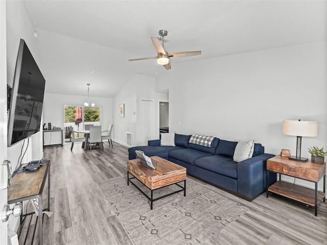 living room with wood finished floors, baseboards, visible vents, vaulted ceiling, and ceiling fan with notable chandelier