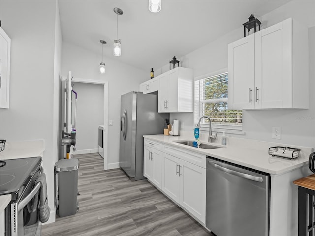 kitchen with a sink, appliances with stainless steel finishes, light countertops, and white cabinetry