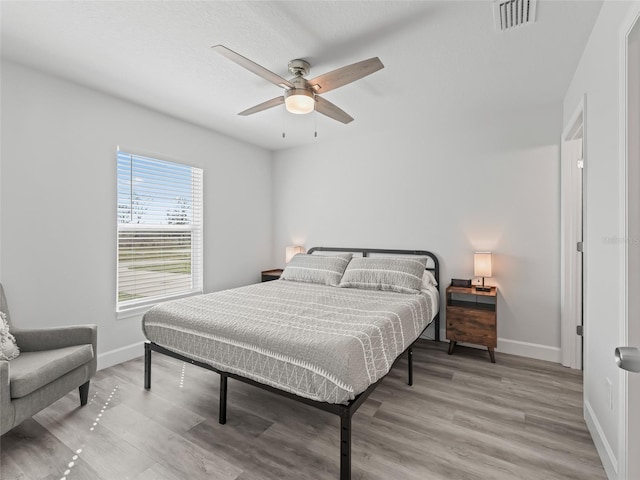 bedroom featuring light wood-style floors, visible vents, and baseboards