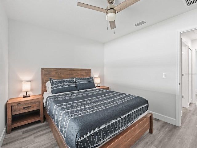 bedroom with ceiling fan, wood finished floors, visible vents, and baseboards