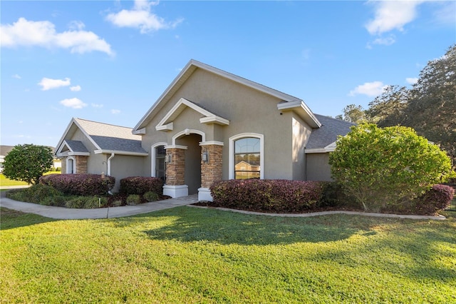 view of front of home with a front lawn, stone siding, roof with shingles, and stucco siding